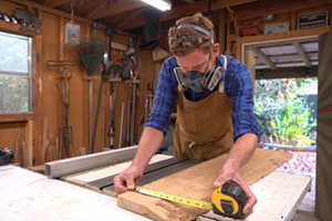 Woodworker Michael Everhart measures a wood plank
